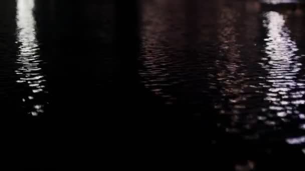 Abstracte reflecties op het wateroppervlak. Reflecties van lantaarns in het zwembad. Gekleurde gloeiende vlekken in het donker. Lichte rimpelingen op het wateroppervlak reflecteren licht. Mooi bokeh licht — Stockvideo