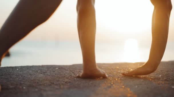 Entraînement matinal. Réchauffez-vous et étirez-vous avant de vous entraîner sur la jetée. Jeune homme pratiquant youga dans le contexte de la mer et le soleil levant. Activité sportive. Silhouette d'athlète. — Video