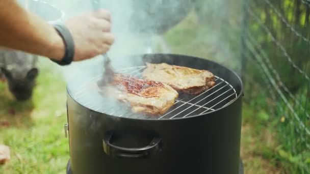 Barbacoa de verano con amigos. Costillas de cerdo asadas. Primer plano de un chefs manos cepillado costillas de cerdo con salsa barbacoa casera. Comida sabrosa. Comida al aire libre. La carne a la parrilla está fumando en la red de parrilla. — Vídeos de Stock