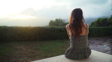 Güzel bir yaz akşamı. Yeşil elbiseli kız terasta oturur ve dağlarda güzel bir gün batımını seyreder. Yaz soğuğu. Bulutların arasındaki altın ışık. Romantik bir akşam. Genç kadın..