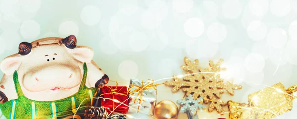 Christmas banner with bull, gifts and snowflakes on a white background with bokeh.