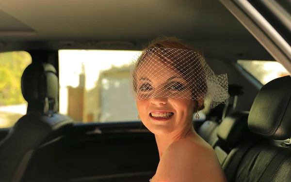 A Mercedes car offers a lot of comfort and luxury to a smiling bride. The bride is seated to be driven off to the church for the wedding ceremony.