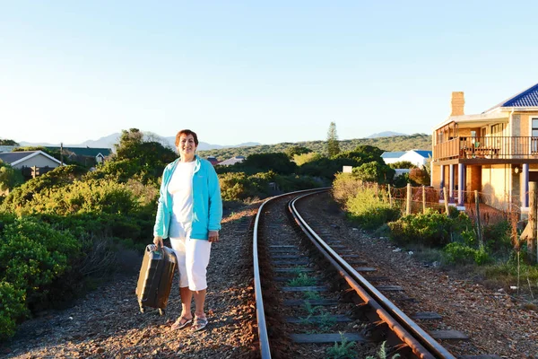 In South Africa trains and busses are not always on time. Sometimes you have to wait. This lady is in a hurry to get to her destination and waits for the train to come on a very desolated station.