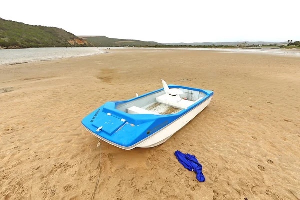 Two boats of holiday makers anchored on the Kleinbrak River bed close to the river mount at the coast on a cloudy day.