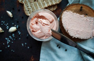 Bıçaklı somon makarnası, dilimlenmiş kızarmış ekmek, karabiber, deniz tuzu, kahverengi paslı arkaplan dokusunda keten peçetede sarımsak. Yukarıdan bak. Bıçağın üzerindeki ezme