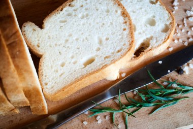 Dilimlenmiş glütensiz beyaz ekmek, tuz ve biber, ahşap arka planda otlar..