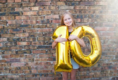10. yaş gününde balon tutan güzel bir kız. Mesajın için yer aç. Doğum günü kutlaması konsepti.