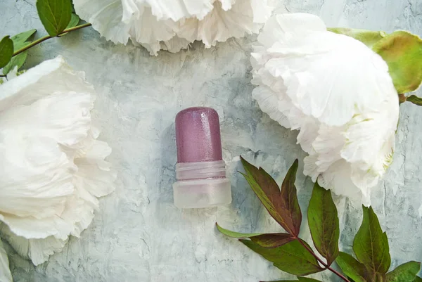 Natural cosmetic. Natural deodorant made from crystalline alum against a background of peonies. Green lifestyle concept, zero waste. Stop plastic pollution. Place for text.