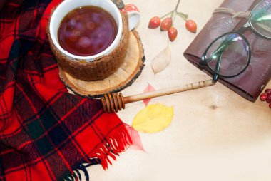 Honey Dipper yakın çekim, seçici odaklanma. Bir fincan limonlu sıcak çay örülmüş sıcak kış eşarbıyla ahşap bir arka planda..