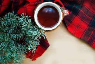Kış arkaplanı bir Noel ağacı dalı. Bir fincan limonlu sıcak çay, ahşap arka planda örülmüş sıcak bir kış eşarbı..