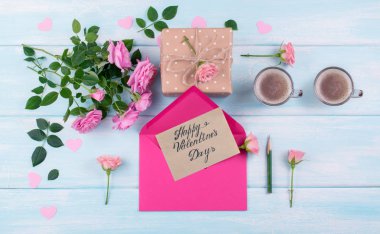 Sevgililer Günü teması. Gül buketi, iki kahve fincanı, Kraft Kağıt zarf ve hediye kutusunda metin üzerinde eski püskü ahşap masa tebrik ile üstten görünüm.  