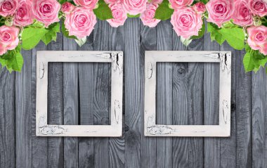 Ahşap arka planda pembe güller ve vintage fotoğraf çerçevesi
