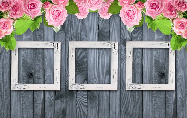 Roze rozen en vintage fotolijstjes op houten achtergrond — Stockfoto