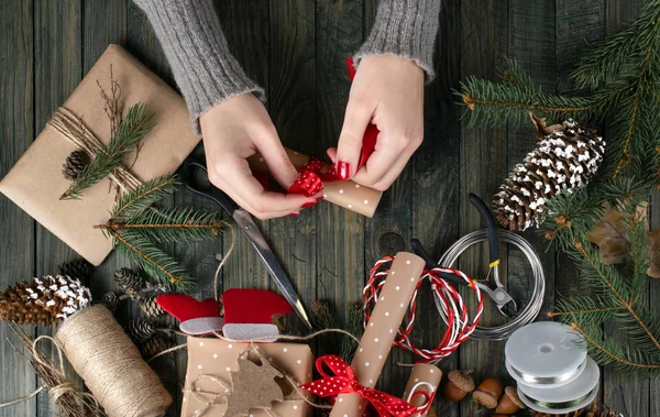 Tema del workshop di Natale. Vista dall'alto delle mani della donna che avvolgono il regalo di Capodanno e il papillon — Foto Stock