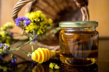 arka planda dipper ve çiçekler ile kavanozda bal