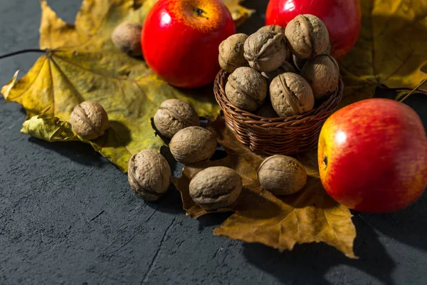 Karanlık bir sonbahar arka planında elmalar ve fındıklar