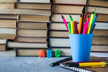 İlkokulda masanın üstünde bir yığın kitap ve kalem vardı. Bir yığın renkli kitap var. Eğitim geçmişi. İş eğitimi konsepti. Metin için alanı kopyala.