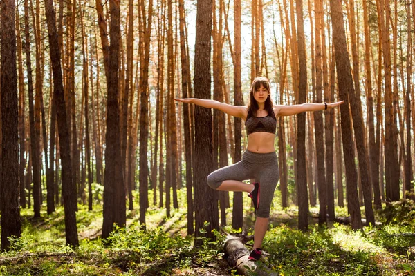 Yoga in the morning summer forest, outdoors with the effect of light. Yoga Woman. The concept of a healthy lifestyle and relaxation.