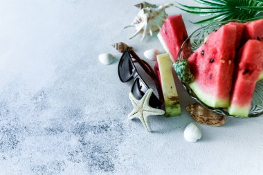 Deniz kabukları, yıldızlar ve palmiye yapraklarıyla sağlıklı bir diyet meyvesi. Tatlı buzlu şekerler yazın hafif arka planda bir dilim karpuz. tasarım için kopyalama alanı