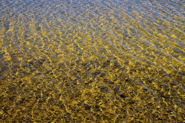 Çakıl taşlı kumlu alt dalgacıkları ile şeffaf su yüzeyi