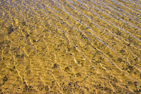 Çakıl taşlı kumlu alt dalgacıkları ile şeffaf su yüzeyi