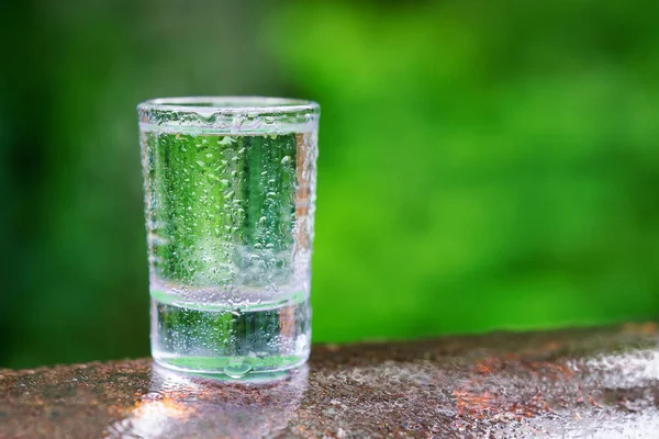 glass of cool clean water on green blurred background
