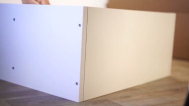 Mobilya montaj iş. Adam bir ahşap dolap üzerinde fişler yüklüyor