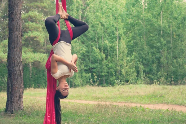 Young woman practicing fly yoga asana outdoors. Health, sport, yoga concept