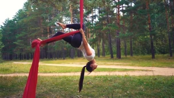 若い女性が空中ヨガ運動や反重力ヨガの屋外練習します 飛んで フィットネス ストレッチ バランス 健康的なライフ スタイルの人々 ハンモックを使用して女性 — ストック動画