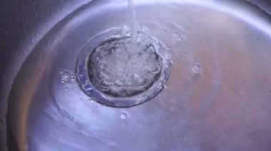 Metal evye. Lavaboda su akış. Su akışı boşa gidiyor.