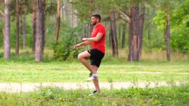 Erkek koşucu eğitimi. Parkta kaslarını esneten erkek sporcu. Sağlıklı, sağlıklı, sağlıklı bir yaşam tarzı. Spor, kardiyo, egzersiz konsepti