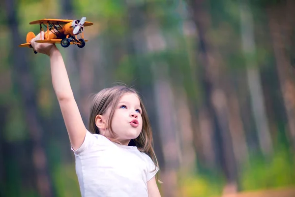 小さな女の子がおもちゃの飛行機を屋外で遊んで 旅の夢 — ストック写真