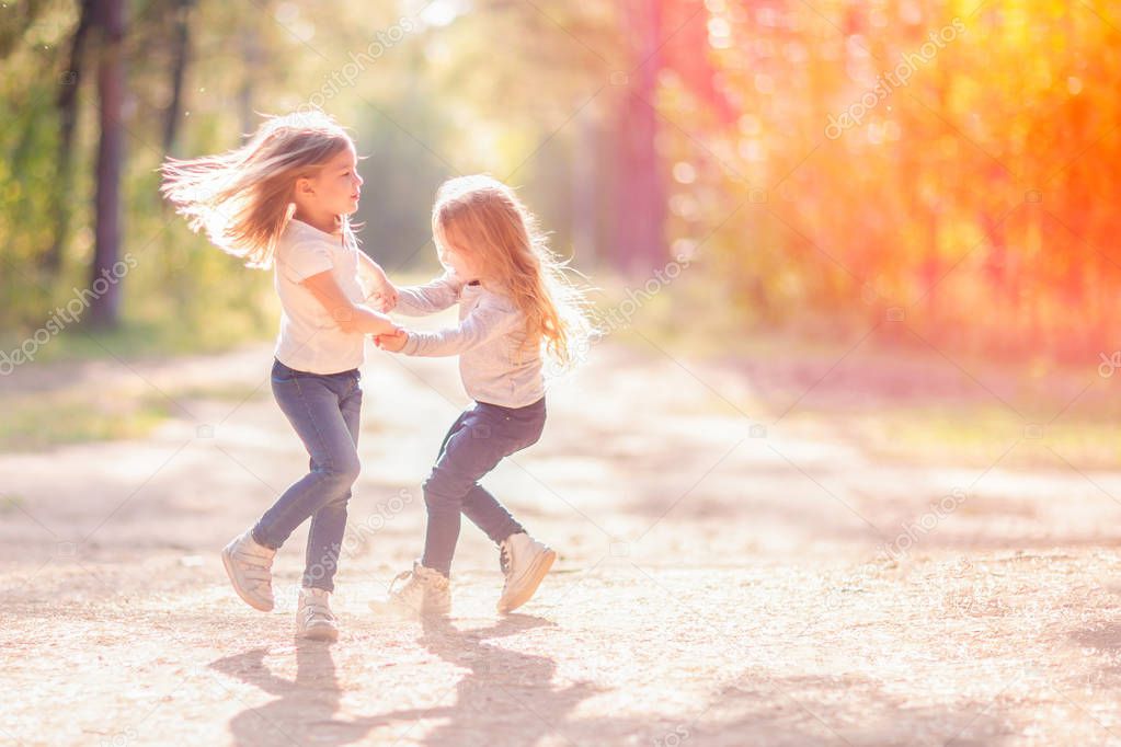 Two little girls dancing and having fun together outdoors