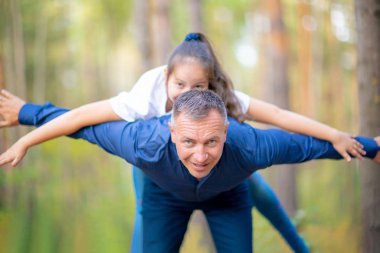 Baba ve kız parkta birlikte vakit. Kız babasının sırtüstü yatıyor.