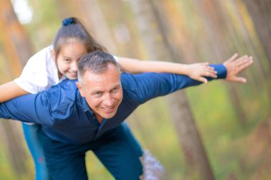 Baba ve kız parkta birlikte vakit. Kız babasının sırtüstü yatıyor.