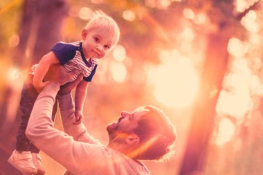 Genç Baba oğlu tutar. Adam bir yaz parkta küçük bebeği ile eğleniyor. Mutlu baba çocuk kadar açık havada oynarken atar