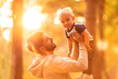Genç Baba oğlu tutar. Adam bir yaz parkta küçük bebeği ile eğleniyor. Mutlu baba çocuk kadar açık havada oynarken atar