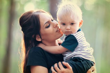 Genç Anne küçük oğlu yaz parkta sarılma. Bebek açık havada kadınla.