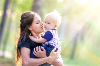 Anne ve bebek birlikte. Genç Anne oğlu sarılmak. Kadın parkta yürüyen bir çocukla. Anne sevgi ve bakım 