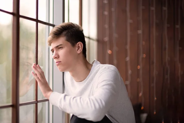 Portret Przystojny Młody Mężczyzna Patrząc Przez Okno Smutek Nastolatek Lat — Zdjęcie stockowe