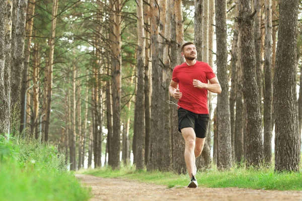 Running man. Male runner jogging at the park. Guy training outdoors. Exercising on forest path. Healthy, fitness, wellness lifestyle. Sport, cardio, workout concept