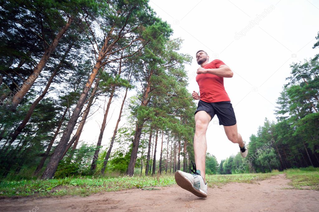 Running man. Male runner jogging at the park. Guy training outdoors. Exercising on forest path. Healthy, fitness, wellness lifestyle. Sport, cardio, workout concept