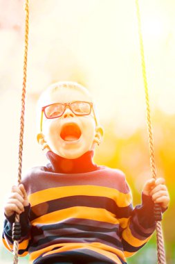 Açık havada üzerinde sallanan komik küçük çocuk gözlük salıncak. 