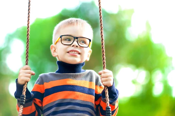 Zabawny Mały Chłopiec Noszenie Okularów Kołysanie Swing Zewnątrz — Zdjęcie stockowe