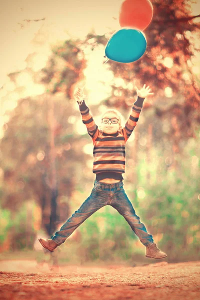 Grappig Jongetje Bril Springen Met Ballonnen Buitenshuis — Stockfoto