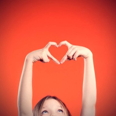 Sevimli küçük kız el şekilden kalp üzerinde kırmızı arka plan yapma. Hareketi seviyorum. Kavram Sevgililer 's gün