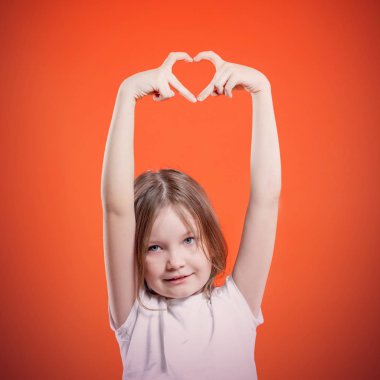 Sevimli küçük kız el şekilden kalp üzerinde kırmızı arka plan yapma. Hareketi seviyorum. Kavram Sevgililer 's gün