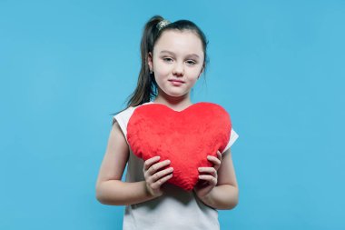 Mavi arka plan üzerinde kırmızı kalp tutan kız mutlu çocuk. Aşk kavramı.