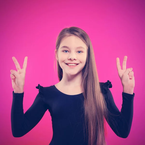 微笑的女孩在粉红色的背景显示和平的姿态 2号胜利标志 — 图库照片