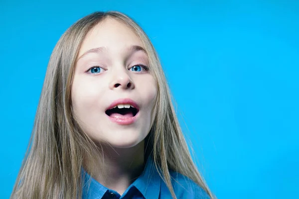 一个可爱的女孩的肖像与开放的嘴在蓝色背景 — 图库照片